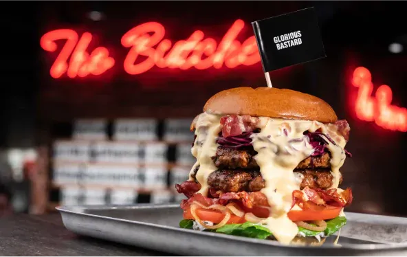 Burger vor der Leuchtschrift „The Butcher“